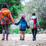 Rodina s deťmi počas turistiky na lesnom chodníku.
