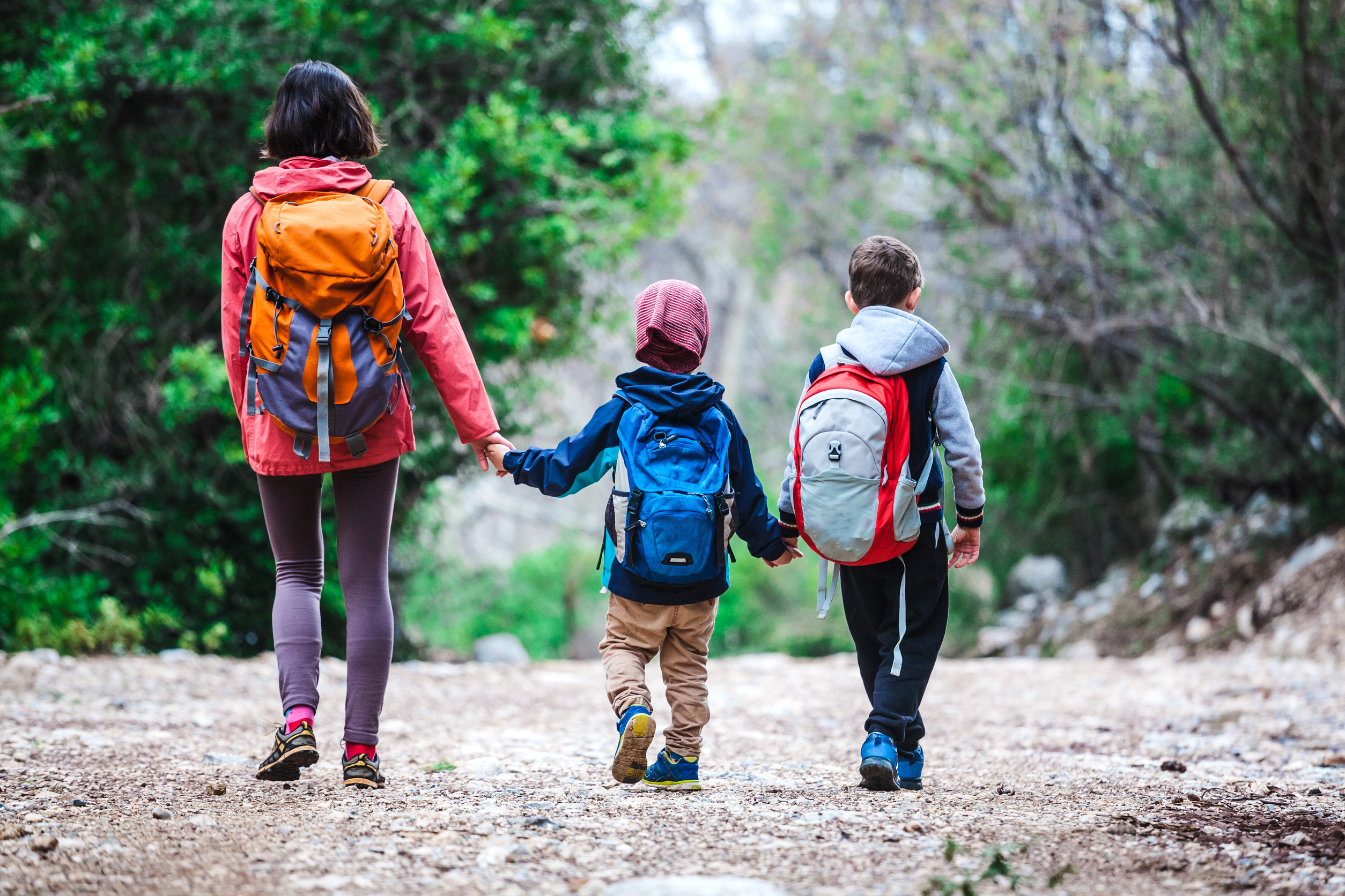 Rodina s deťmi počas turistiky na lesnom chodníku.